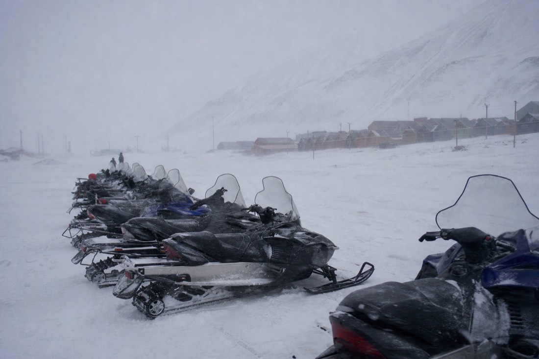 Snowmobiles parked at the edge of Longyearbyen as weather closes in, a common reason Svalbard tours cancel