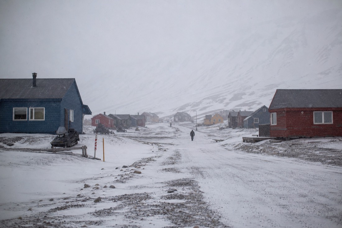 Coloured Longyearbyen houses in low cloud and blowing snow, the weather that reshuffles a Svalbard itinerary