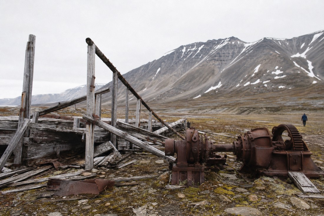 Weathered timber and old mining machinery on Svalbard tundra, protected cultural heritage from before 1946