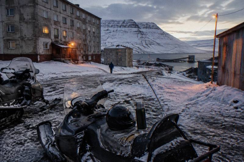 Snowmobiles parked on snow beside a fjord in winter light near Longyearbyen, the kind of route a Barentsburg snowmobile day follows